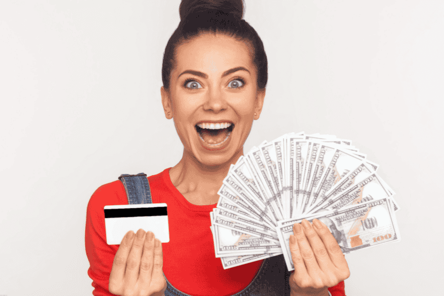 Smiling woman holding a credit card and fanned out hundred-dollar bills