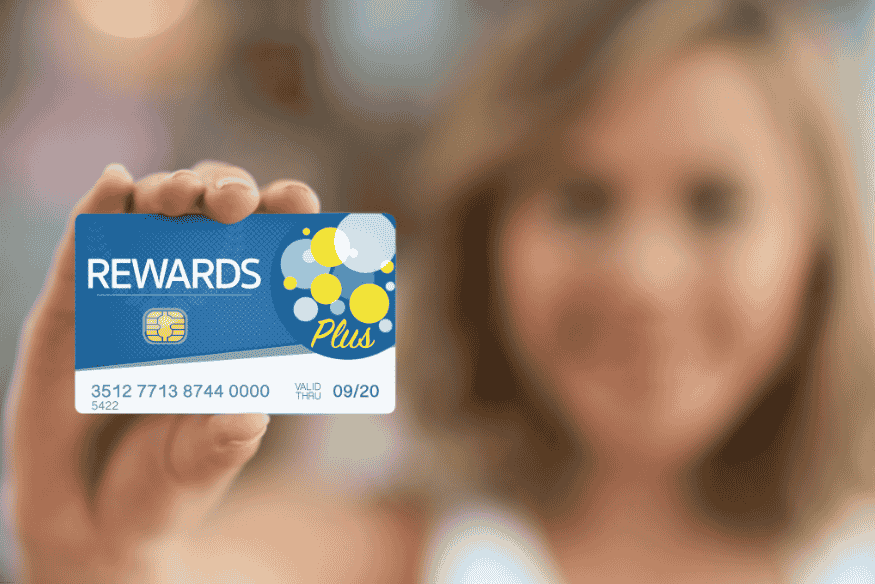 Woman holding a credit card labeled "Rewards Plus"