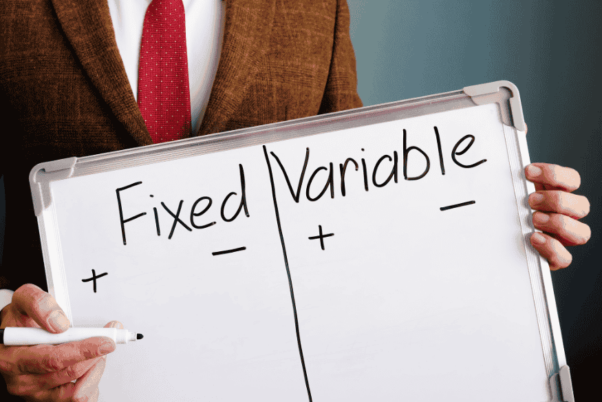 Person holding a whiteboard with the words “Fixed” and “Variable” separated into pros and cons