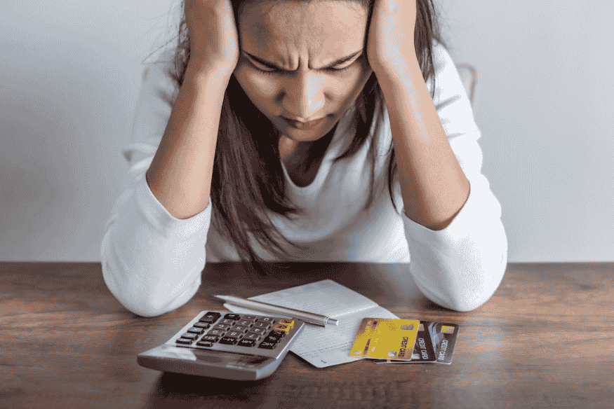 Woman frustrated at her desk with a calculator and multiple credit cards