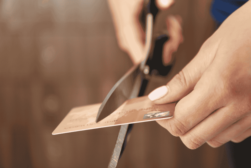 Person cutting a credit card in half with scissors